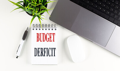 BUDGET DEFICIT text on notebook with laptop, mouse and pen