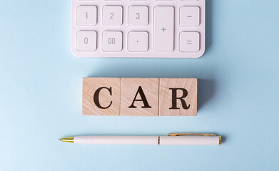 CAR word on wooden block with pen and calculator on blue background