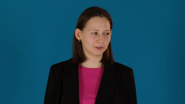 Serious woman looks away talking on blue background. Lady eyes fixate on distant point speaking with measured and composed tone