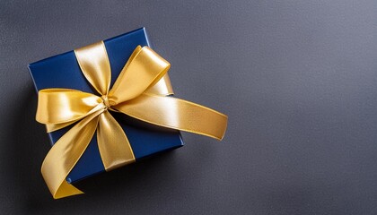 dark blue gift box with elegant gold ribbon on dark background top view of greeting gift with copy space for christmas present holiday or birthday