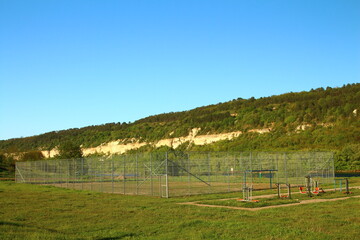 A field with a fence and a hill in the background