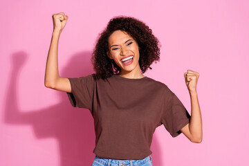 Photo of nice young girl raise fists wear brown t-shirt isolated on pink color background