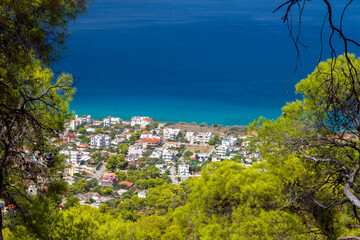 Aianteio town, panoramic view of this seaside town in Salamina island, Greece, as seen through the branches of pine trees, complemented by the sea.