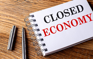 CLOSED ECONOMY text on notebook on grey background
