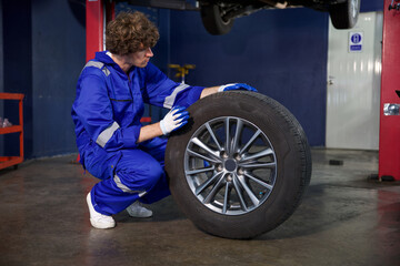 mechanic holding and checking a tire for fixing in garage