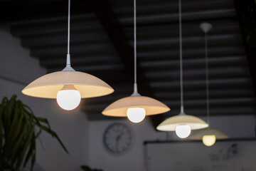 Ceiling fixture with lamps in tints and shades, clock in background