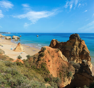 Evening sandy beach Praia dos Tres Castelos with rock formations, Portimao, Algarve, Portugal. Top view. Peoples are unrecognizable.