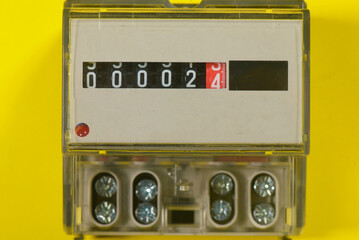 Electricity meter close up on the yellow flat lay background.