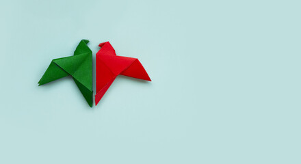 banner two doves made of origami paper in red and green colors facing each other on pastel blue...