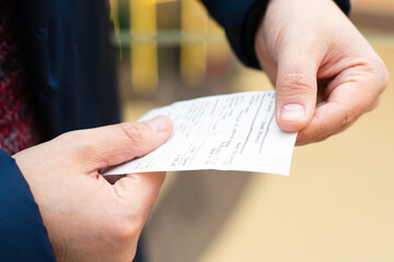paper grocery shopping receipt in male hands close-up. Blank check from shop, supermarket or...