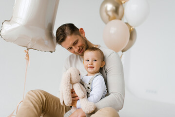 Smiling father looks at his son against the background of festive balloons in the studio
