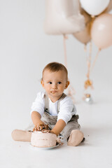 One year old boy eats his first birthday cake with his hands