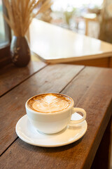 Hot coffee latte with latte art milk foam in cup mug on wood desk on top view. As breakfast In a coffee shop at the cafe,during business work concept,vintage style