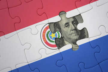 puzzle with the national flag of paraguay and usa dollar banknote. finance concept