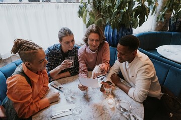 Diverse friends checking out menu at a restaurant - Powered by Adobe