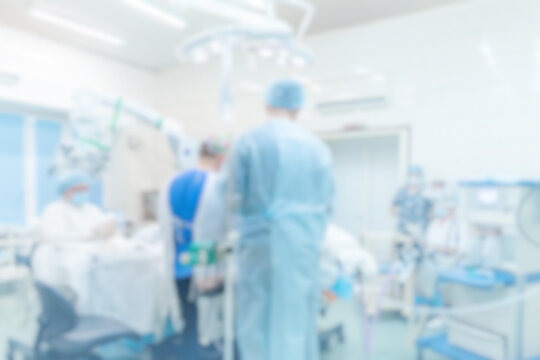Abstract medical blurred background of operating room with blue light, patient lies on table, doctors working
