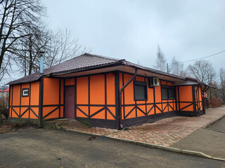The beautiful orange facade of a one-story house. The house stands near the park on a cloudy spring...