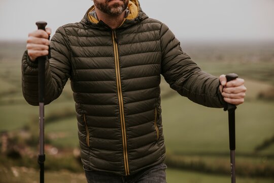 Man wearing jacket, holding hiking pole