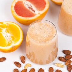 Fruit smoothie in a glass, grapefruit and orange on white background.