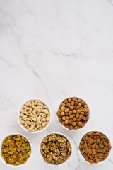 Various nuts and dried fruits in white bowls