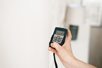 Measuring the length and area of a room during renovation with a laser rangefinder in a woman's hand