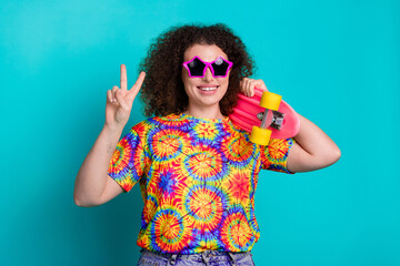 Photo of lovely cheerful woman wear trendy vivid print clothes hand hold board v-sign isolated on cyan color background