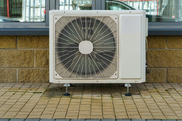 Outdoor air conditioning unit. A large modern air conditioner on the wall of an apartment building....