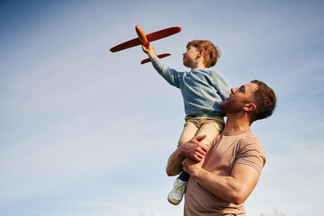 Blue sky with white cloud. Father is holding son that playing with toy plane