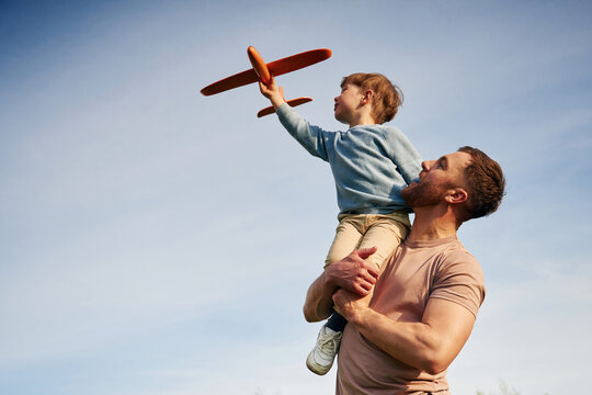 Blue sky with white cloud. Father is holding son that playing with toy plane