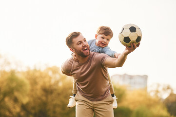 Real football, soccer ball. Happy father with son are having fun on the field at summertime