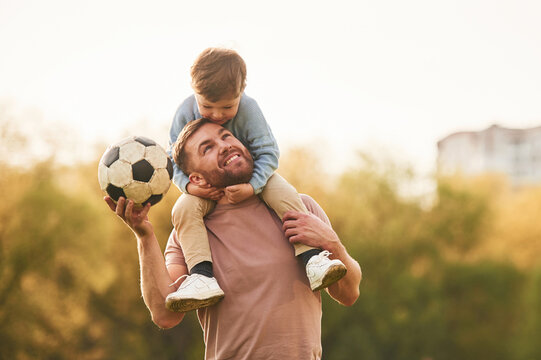 Real football, soccer ball. Happy father with son are having fun on the field at summertime