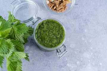 Creamy nettle pesto sauce in jar on a gray background. Appetizer, condiment or topping. Healthy vegan food. top view
