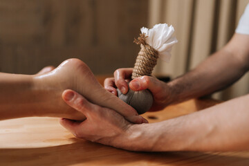 Cropped shot of unrecognizable relaxed woman getting Ayurvedic feet massage with Kizhi Herbal Bags...