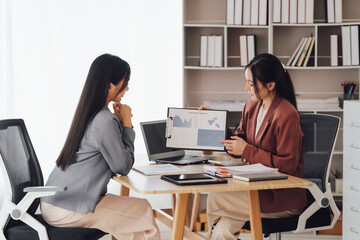 Two young Asian business woman talk, consult, discuss working with new startup project idea...