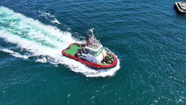 Aerial drone top down video of industrial tug assisting boat cruising in deep blue Mediterranean sea