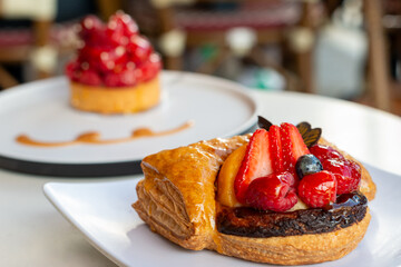 Round shaped fruit filled French puff pastry on white plates. The cream and custard filled dessert...