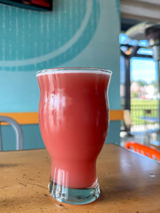 A clear nonic pint glass filled with a red berry flavored beer. The craft alcohol draught ale has a bold taste with a refreshing cold moisture on the outside of the glass and thick foam on top. 