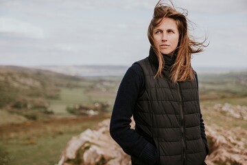 Woman in black puffer vest standing on mountain photo