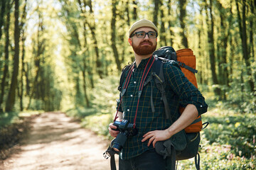 Front view. Bearded man is in the forest at daytime