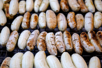 grilled banana on hot charcoal stove in Thai street food market 