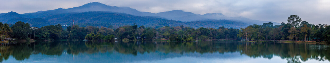 Fototapeta premium Ang Kaew lake with Doi Suthep mountains background in cloudy sky, Chiang mai , Thailand