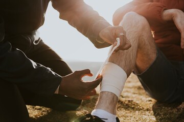 Man putting bandage on friend's leg photo