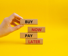 Buy now Pay later symbol. Concept word Buy now Pay later on wooden block. Businessman hand. Beautiful yellow background. Business and Buy now Pay later concept. Copy space