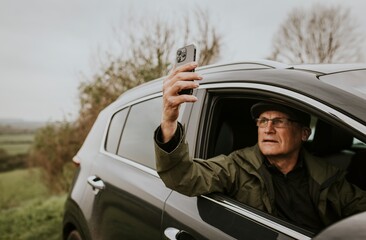 Naklejka premium Senior man driving, using GPS on smartphone