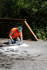 City parks workman grinding down concrete at the end of a bridge to level it off with the asphalt path for safety
