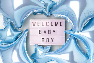 Welcome baby boy. Lightbox with letters and inflatable foil balloons in a blue color. Creative...