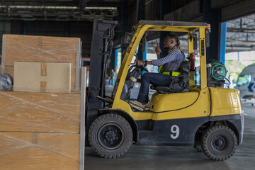 Man worker at forklift driver happy working in industry factory logistic ship. Man forklift driver in warehouse area. Forklift driver sitting in vehicle in warehouse.