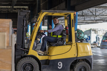 Man worker at forklift driver happy working in industry factory logistic ship. Man forklift driver in warehouse area. Forklift driver sitting in vehicle in warehouse.