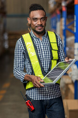 Man Worker holding a photovoltaic solar panel in warehouse. Happy Man with solar panel. Smiling...
