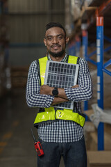 Man Worker holding a photovoltaic solar panel in warehouse. Happy Man with solar panel. Smiling...